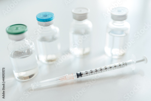 Bottles of vaccine vial and syringe on the white table.