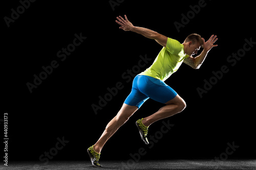 Caucasian professional male athlete, runner training isolated on black studio background. Muscular, sportive man. Concept of action, motion, youth, healthy lifestyle. Copyspace for ad.