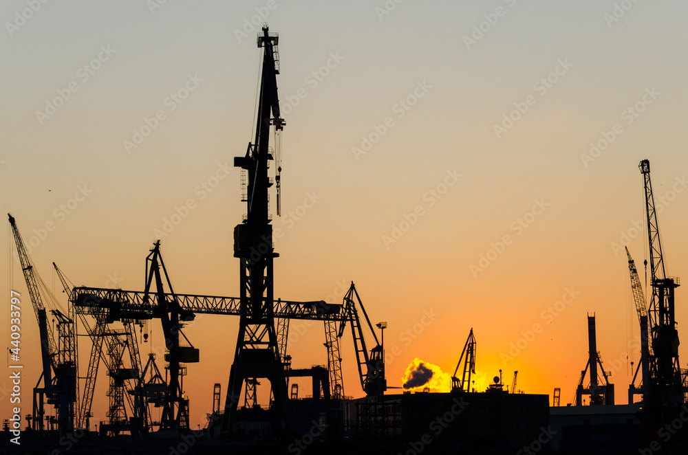 Silhouette of harbour cranes and container terminal during scenic sunset in Hamburg, Germany
