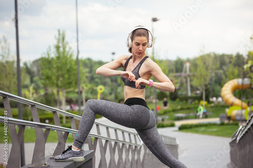 Young female runner, athlete is in the city street in spring sunshine. Beautiful caucasian woman training, listening to music. Concept of sport, healthy lifestyle, movement, activity.