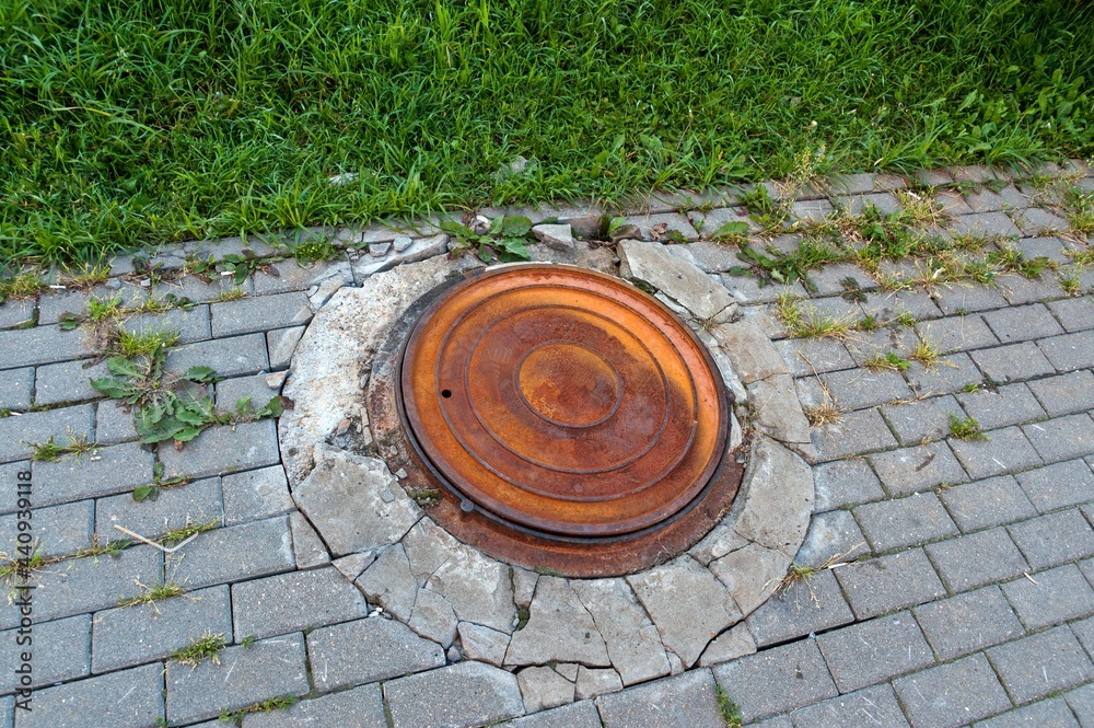 The lid of the water well on the sidewalk was rusted