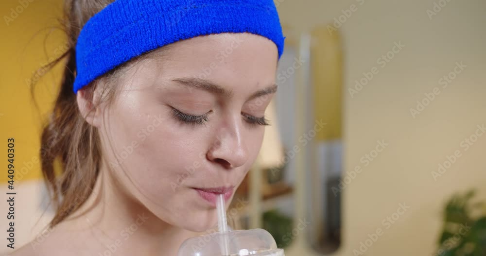 Portrait of the young female athlete looking at the camera and drinking unhealthy cola during the training. Weight loss, fitness, will power, choice between healthy and unhealthy lifestyle concept Portrait of the young female athlete looking at the camera and drinking unhealthy cola during the training. Weight loss, fitness, will power, choice between healthy and unhealthy lifestyle concept