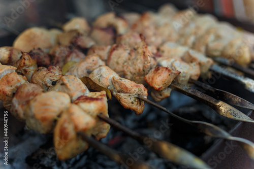 Soft focused shot of marinaded pork meat pieces on skewers frying over bonfire. Kebab or traditional shashlik cooking with lot of smoke.