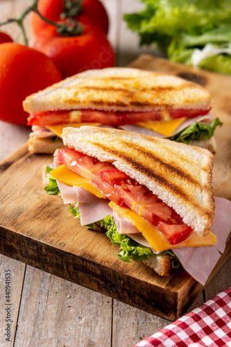 Sandwich with tomato lettuce ham and cheese on wooden table 