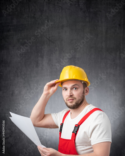 A confused construction worker holding papers or documents