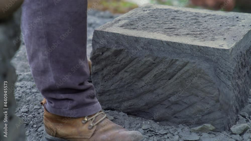 Handheld dolly shot of a stone craftsman using a pick to edge a large stone brick, in the city of Ancud, on the island of Chiloe. Handheld dolly shot of a stone craftsman using a pick to edge a large stone brick, in the city of Ancud, on the island of Chiloe.
