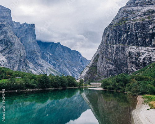 Detailed layered mountain cliffs and trees over a river