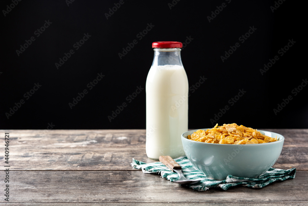 Corn flakes in a blue bowl and milk bottle on rustic wooden table. Copy space