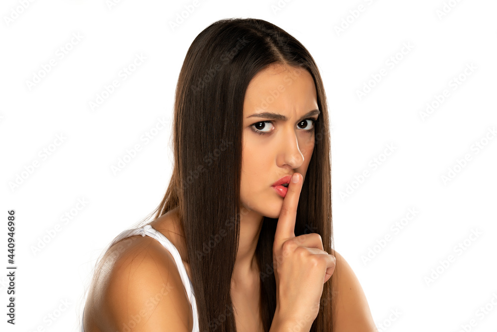 portrait of a frowning woman with a finger in front of her lips portrait of a frowning woman with a finger in front of her lips