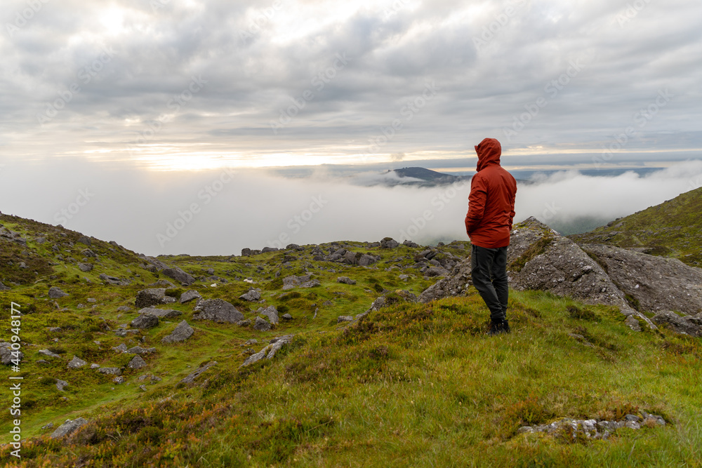 Man standing on top of mountain admiring landscape with mist