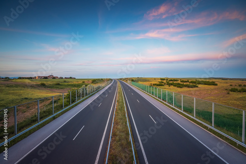 Aerial view of highway on sunset. Transportation background. Landscape with road near countryside fields © ValentinValkov