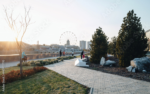 Architectural project near the river Miass in Chelyabinsk. People walking in garden in autumn on sunset