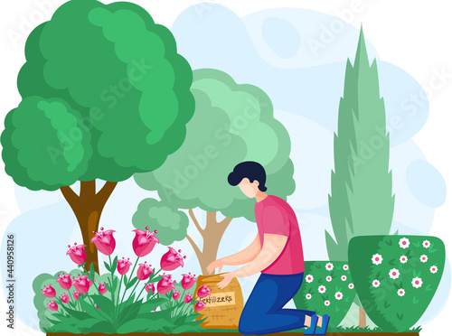 Gardener fertilizes flowers, trees and bushes in garden. Young man cultivates soil and grows plants. Boy is kneeling and holding sack of fertilizer in green park. Guy works on land for agriculture