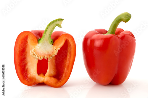 One whole red bell pepper and one cut in half in cross section, isolated on white