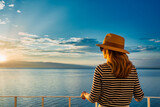 Woman enjoying the sunrise and a perfect sea view while standing on the balcony