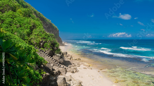 Tropical wild beach with stone staircase. Sandy beach and ocean waves