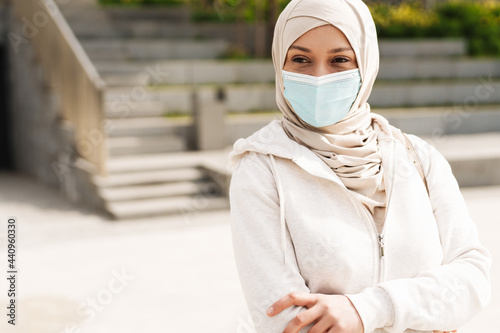 Middle eastern woman in face mask standing while working out outdoors