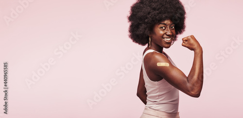 African woman flexing an arm after vaccination