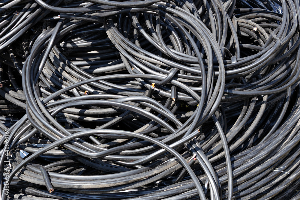 A twisted copper wire in black plastic insulation lies in a pile. Electrification and automation of systems. Consumable material. A twisted copper wire in black plastic insulation lies in a pile. Electrification and automation of systems. Consumable material.