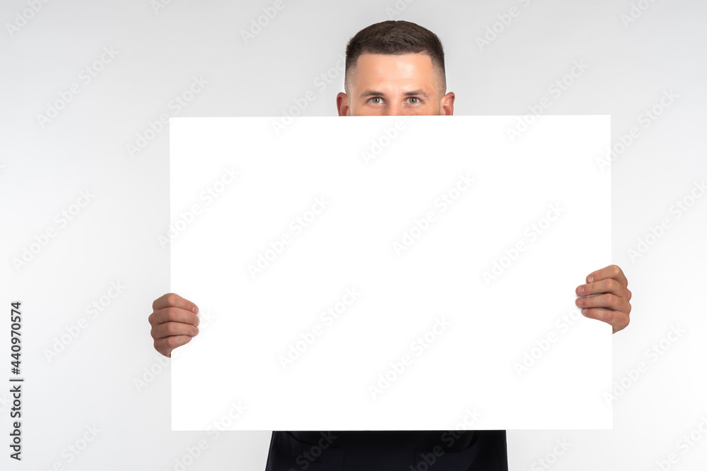 Man with white banner. He shows blank sheet of paper in near of him. Portrait man with a closed face. Large blank poster in front of his face. Place for inscription on his poster. Man with white banner. He shows blank sheet of paper in near of him. Portrait man with a closed face. Large blank poster in front of his face. Place for inscription on his poster.