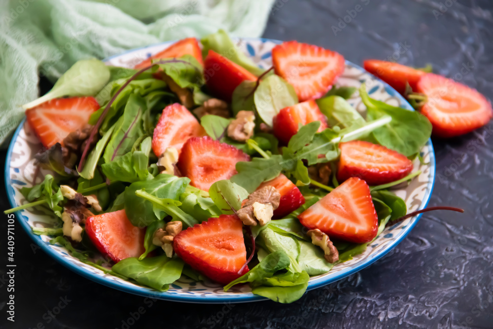 salad with strawberries, nuts on a concrete background