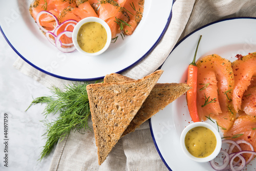 Gravlax Graved Lachs Asiaitsche Art und Klassisch, ein roh gebeizter Fisch mit Zitronengras, Chili, Dill, Hovmästarsås Senf Soße, Toast, Zwiebel Ringe und Zitrone auf Emaille Teller und Leinen Tuch au photo