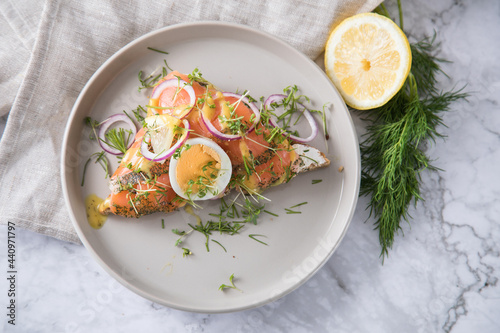 Gravlax Graved Lachs, ein roh gebeizter Fisch auf Toast Brot mit Hovmästarsås Senf Soße, Dill, Kresse, Ei, Zwiebel Ringe, Zitrone und Leinen Tuch auf hell Marmor Hintergrund