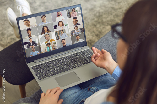 Canvastavla Young business team manager sitting in comfortable chair at home with laptop computer on lap and having virtual meeting with teammates