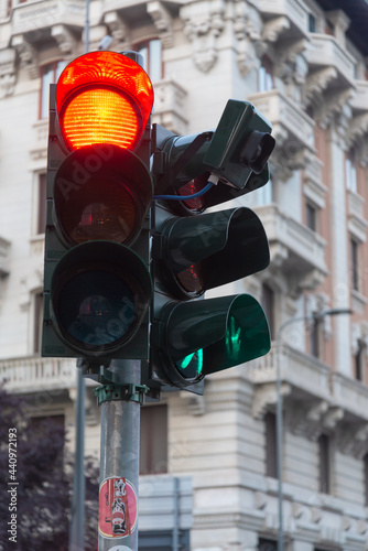 Traffic light with red stop light in urban environment. Blurred building in the background. Milan, Italy.