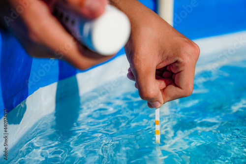 Checking the water quality of a pool with the help of a test strip with PH value, chlorine and algaecide photo