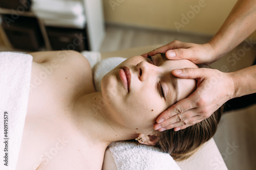 Masseur doing massage on a woman's face at the spa.