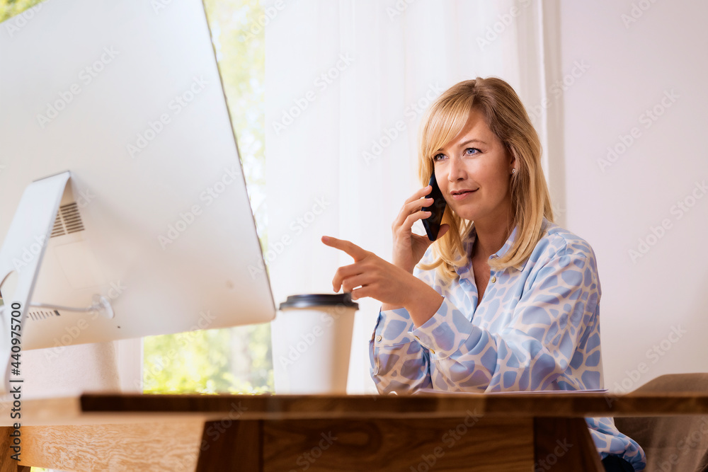 Attractive middle aged woman sitting at desk and working from home Attractive middle aged woman sitting at desk and working from home