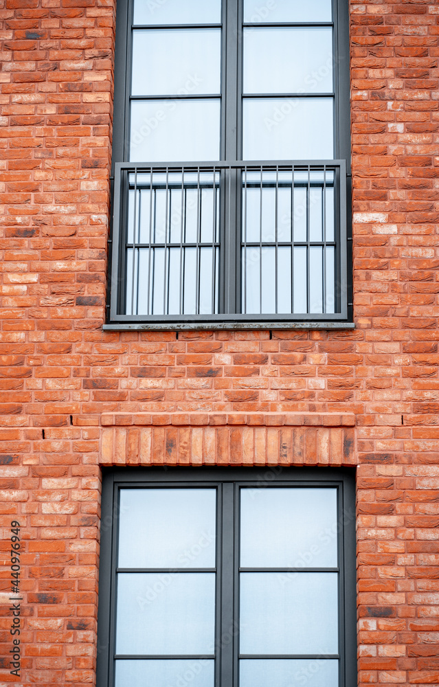Part of the wall of a modern red brick residential building with a large window (897)
