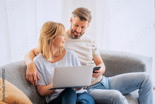 Happy couple relaxing together at home and using laptop