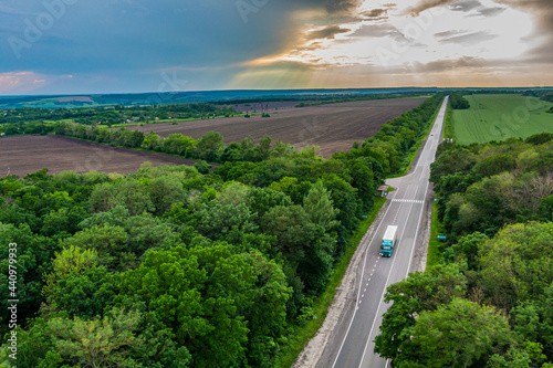 truck driving on asphalt road through a green forestat sunset. Drone top view. Aerial view landscape. photo