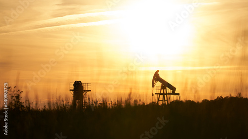 Background image of oil pumping machines at sunset. Copy space.