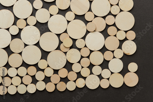 background composed of thin, untreated or natural round wooden shapes - loosely arranged on a dark gray ground - photographed in a top-down style 