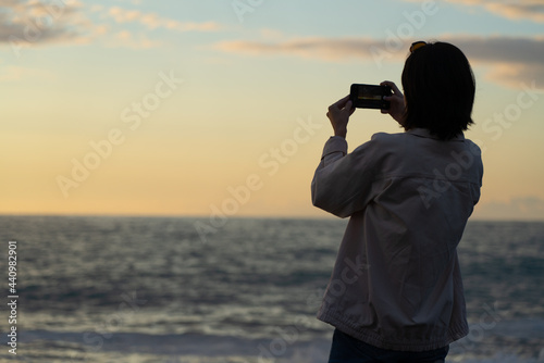 girl photographs the sea sunset