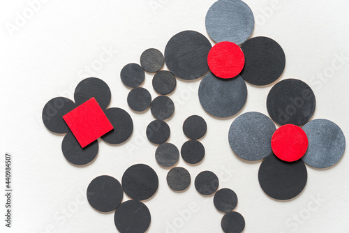 laser-cut plywood shapes (flowers) hand painted in red, silver gray, and flat black loosely arranged on white - photographed from above in a flat lay style