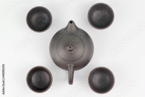 A Chinese black ceramic teapot and teacup isolated on a white background.