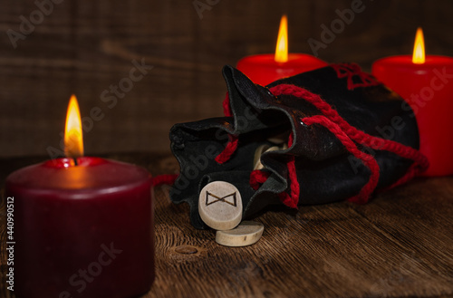 The rune Dagaz means Day. The rune fell out of an antique leather bag against a background of red candles. Selective Focus photo