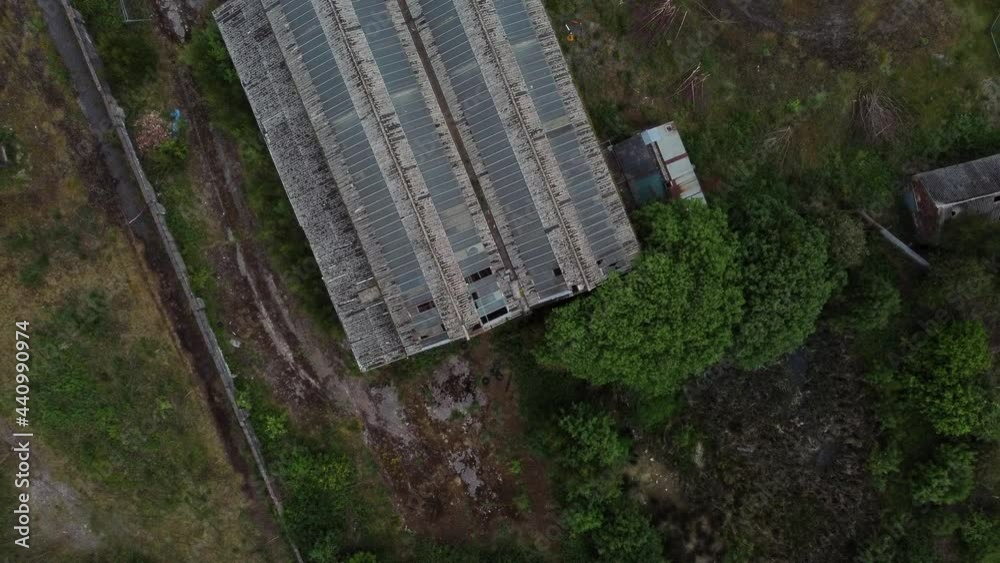 Abandoned aerial top view over broken military warehouse overgrown rooftop ruined base Abandoned aerial top view over broken military warehouse overgrown rooftop ruined base