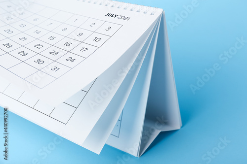 Flip calendar with page of July on color background, closeup
