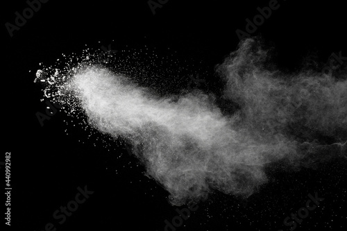White dust particles splashing. Freez motion of talcum powder burst in dark background.