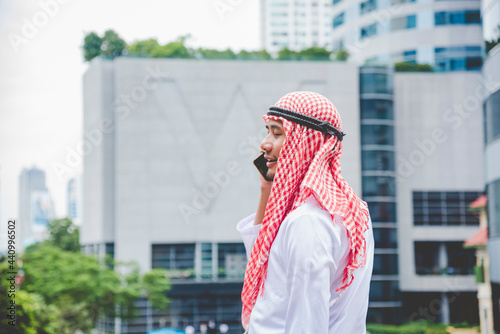 Islamic man using smartphones app organize schedule agenda  focus on hands holding smartphone muslim modern uae city. Arab men wear hijab and muslim formal dress sending text sms online lifestyle photo