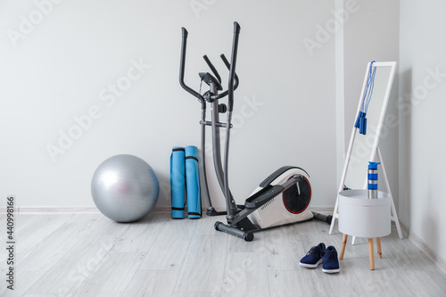 Different sports equipment with fitness ball and mirror near light wall