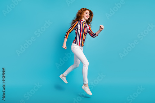 Full length body size view of attractive cheerful girl jumping running fast isolated over blue color background