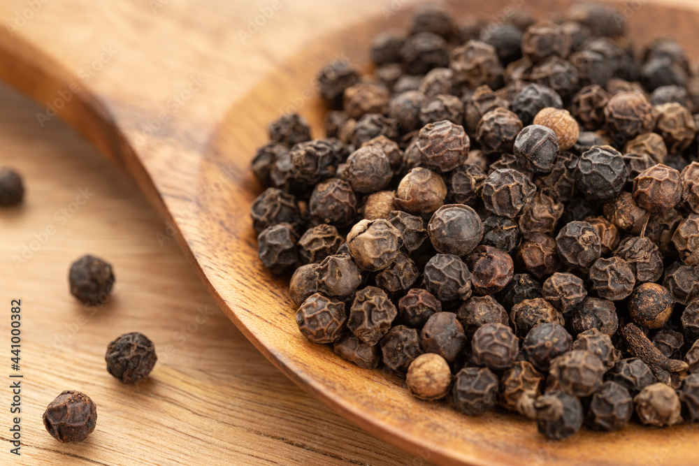 Black pepper or pepercorn on wooden spoon. Cooking Spices. Piper nigrum Black pepper or pepercorn on wooden spoon. Cooking Spices. Piper nigrum