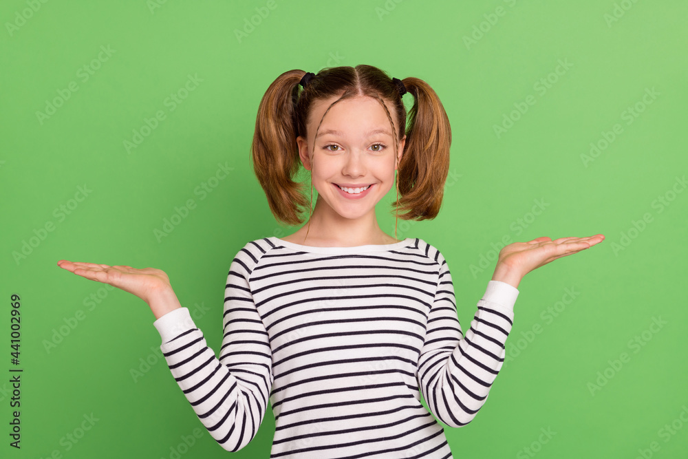 Photo of lovely blond hairdo small girl hold empty space wear striped sweater isolated on green color background Photo of lovely blond hairdo small girl hold empty space wear striped sweater isolated on green color background