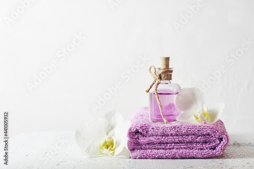 A bottle of lilac perfume and orchid flowers.